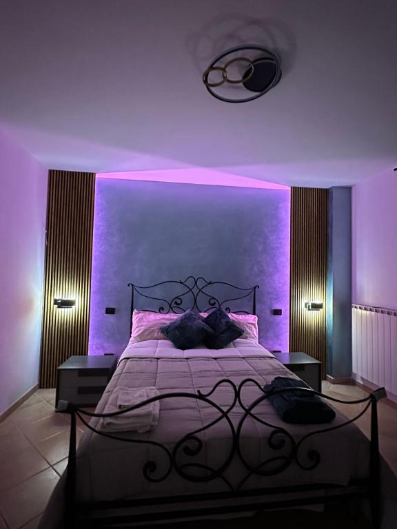 Dormitorio púrpura con cama con iluminación púrpura en La balena bianca house, en Bagni San Filippo