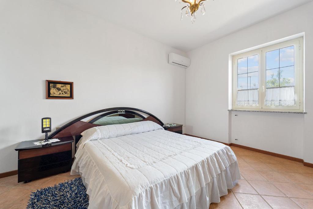 a white bedroom with a bed and a window at Casa del vento 2 in Tratalias