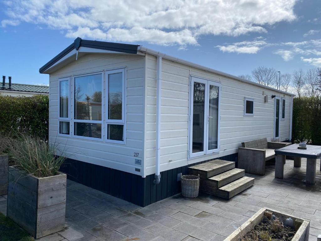 ein weißes winziges Haus mit einem Picknicktisch im Hof in der Unterkunft RBR 237 - Beach Resort Kamperland in Kamperland