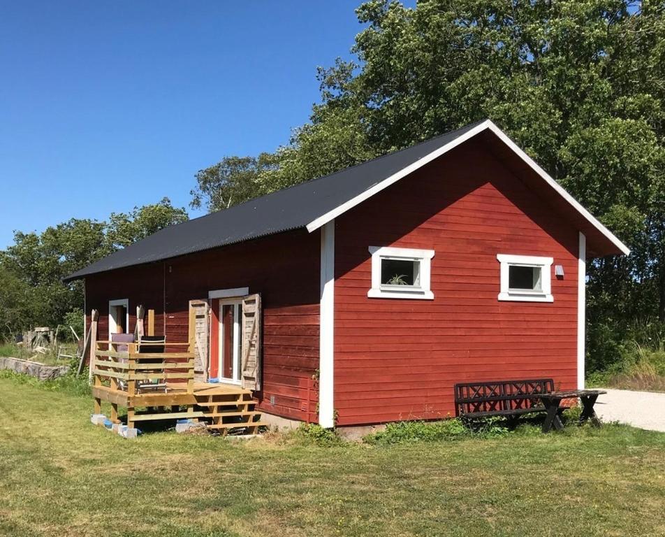 Burgsvik的住宿－Tågmagasinet Fidenäs，一间黑色屋顶的红色小房子