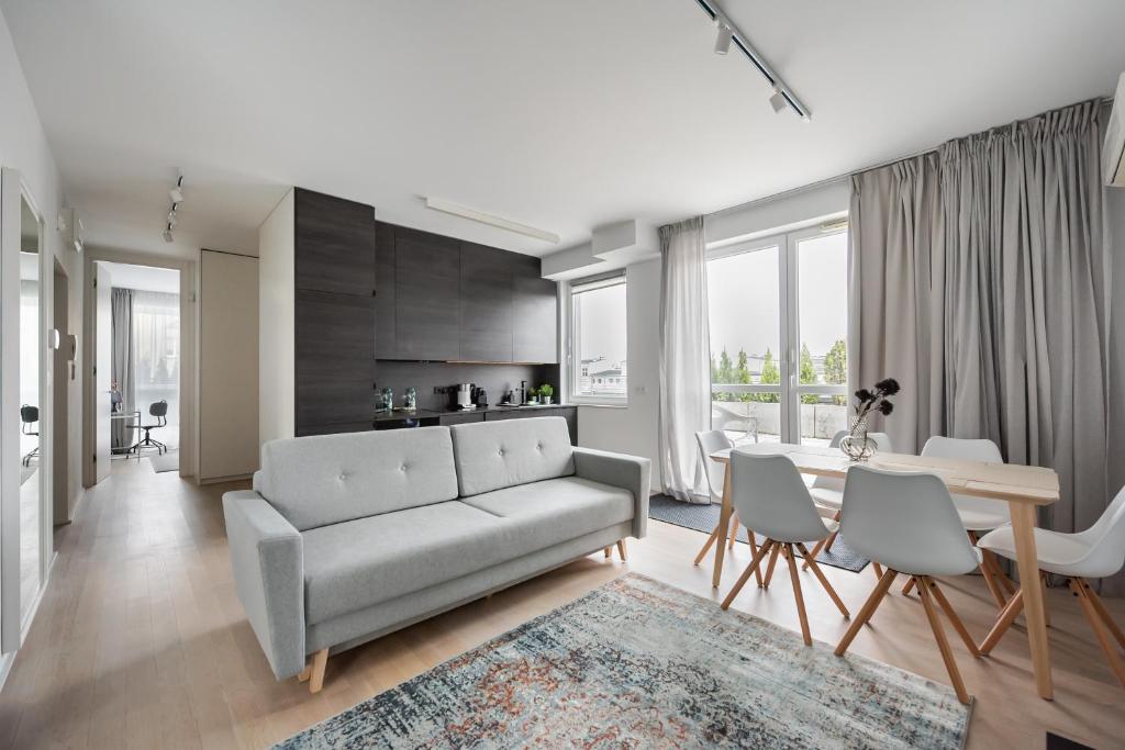 New Praga Urban Modern Apartment في وارسو: غرفة معيشة مع أريكة وطاولة وكراسي