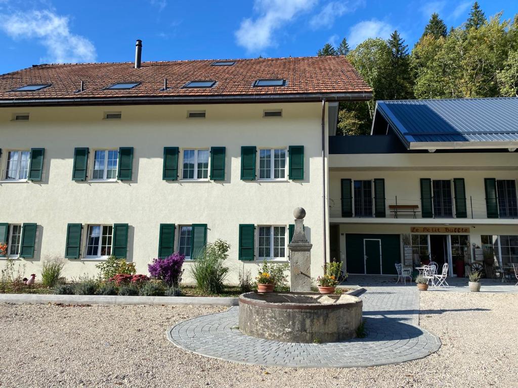 un bâtiment avec une fontaine devant lui dans l'établissement Vacances à la Ferme des Buffles, à Travers