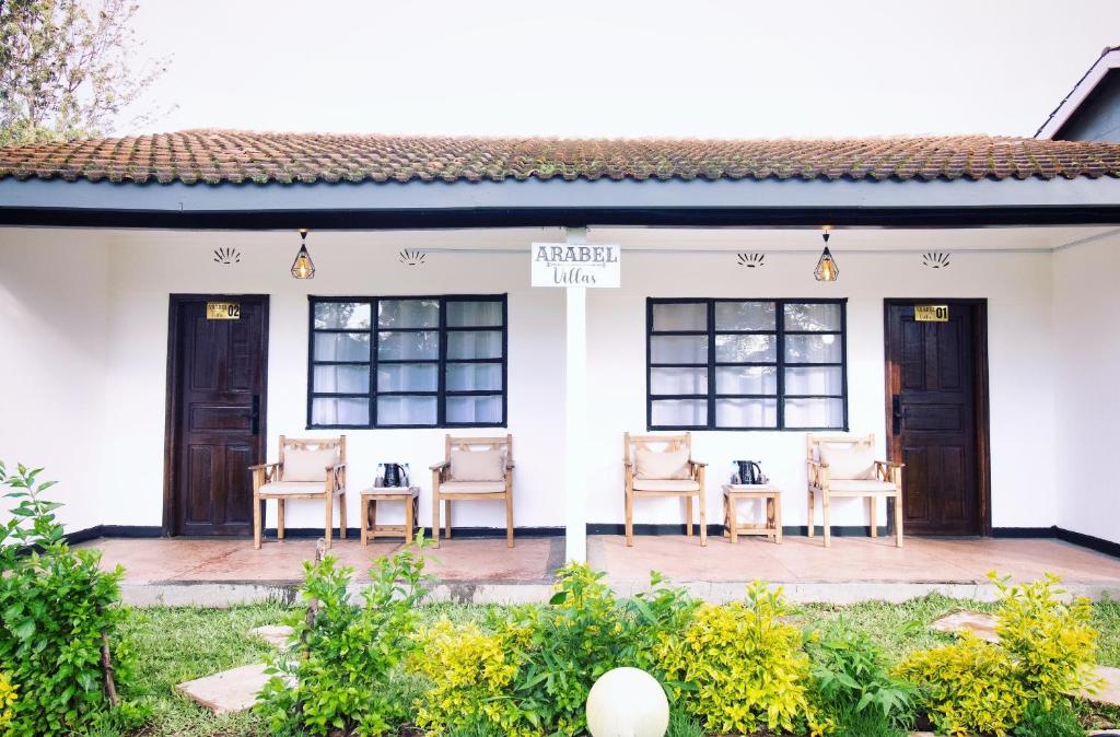 un grupo de sillas sentadas en el porche de una casa en Arabel's Place Riverside Villas, en Nanyuki