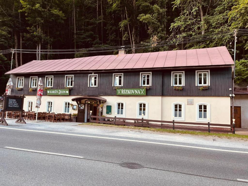 un edificio con techo rojo al lado de una carretera en POD SVATOU ANNOU - penzion a řízkovna, en Horní Maršov