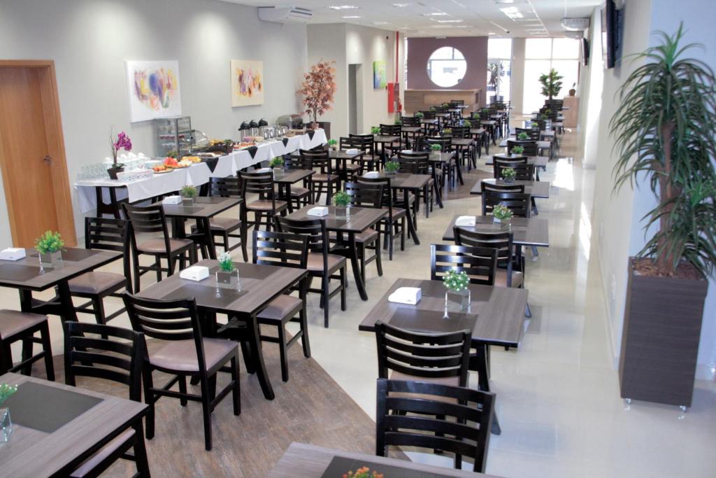 a row of tables and chairs in a restaurant at Ônix Inn Hotel Cravinhos in Cravinhos