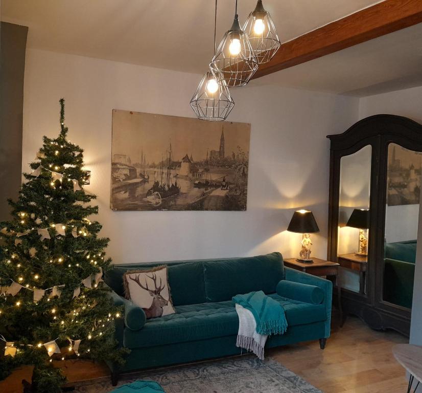 una sala de estar con un sofá verde y un árbol de Navidad en Gîte Le3 Bergheim en Bergheim