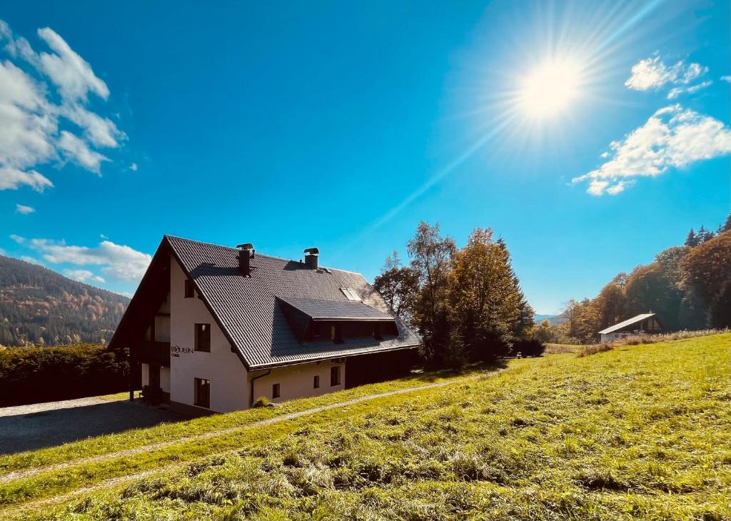 a house on a hill with the sun in the sky at Chata Boubín in Kubova Huť