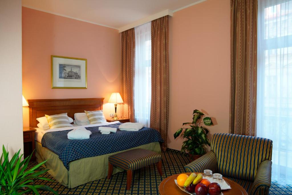 カルロヴィ・ヴァリにあるHotel Villa Laurettaのベッド、テーブル、椅子が備わるホテルルームです。