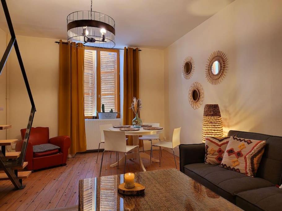 ein Wohnzimmer mit einem Sofa und einem Tisch in der Unterkunft Duplex bohème chic in Gannat