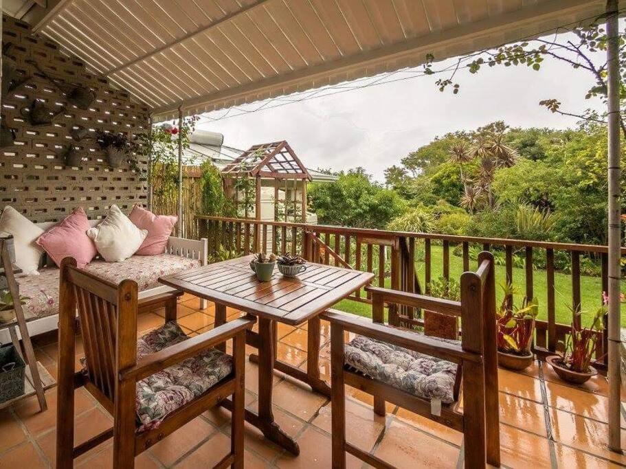 a patio with a table and chairs on a balcony at Rose Cottage in Knysna