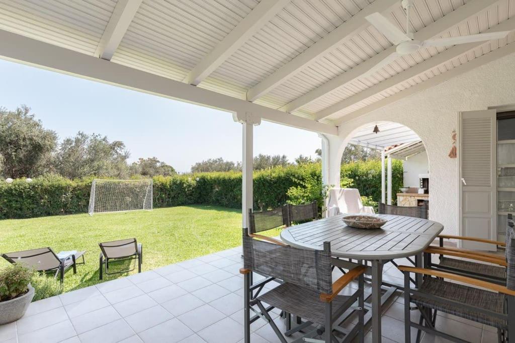 een patio met een tafel en stoelen bij Luxurious villa, with big garden next to beach in Selianitika