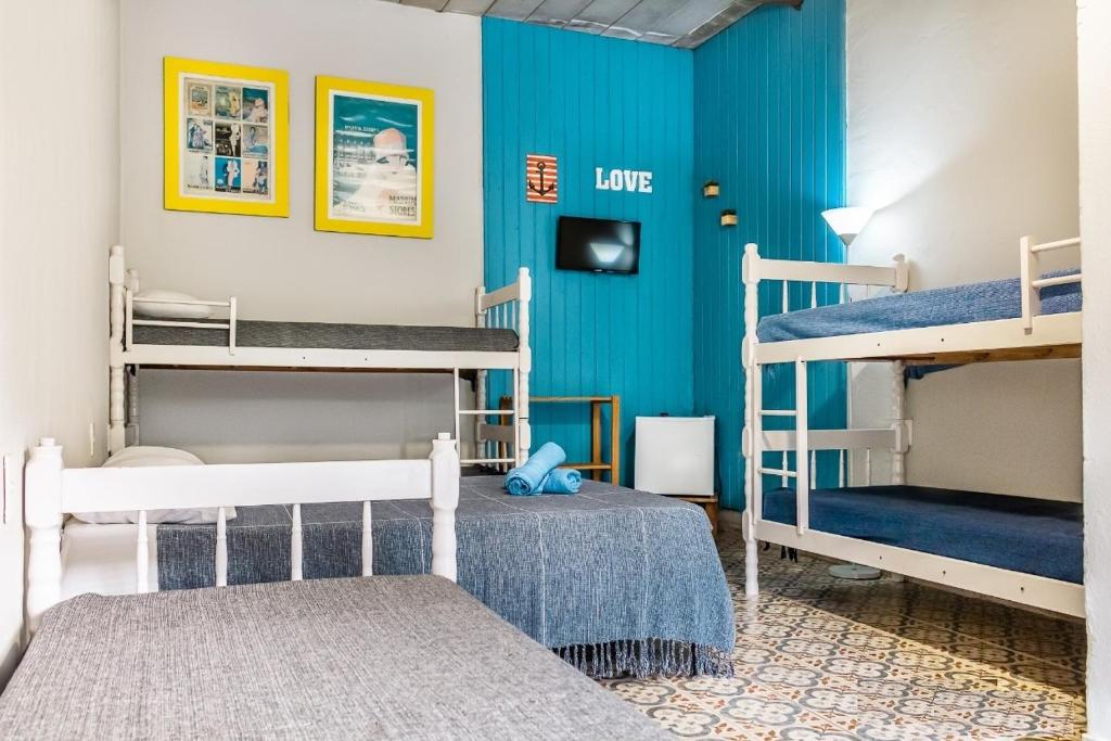 a room with two bunk beds and a blue wall at Vilarejo do Perequê in Ilhabela