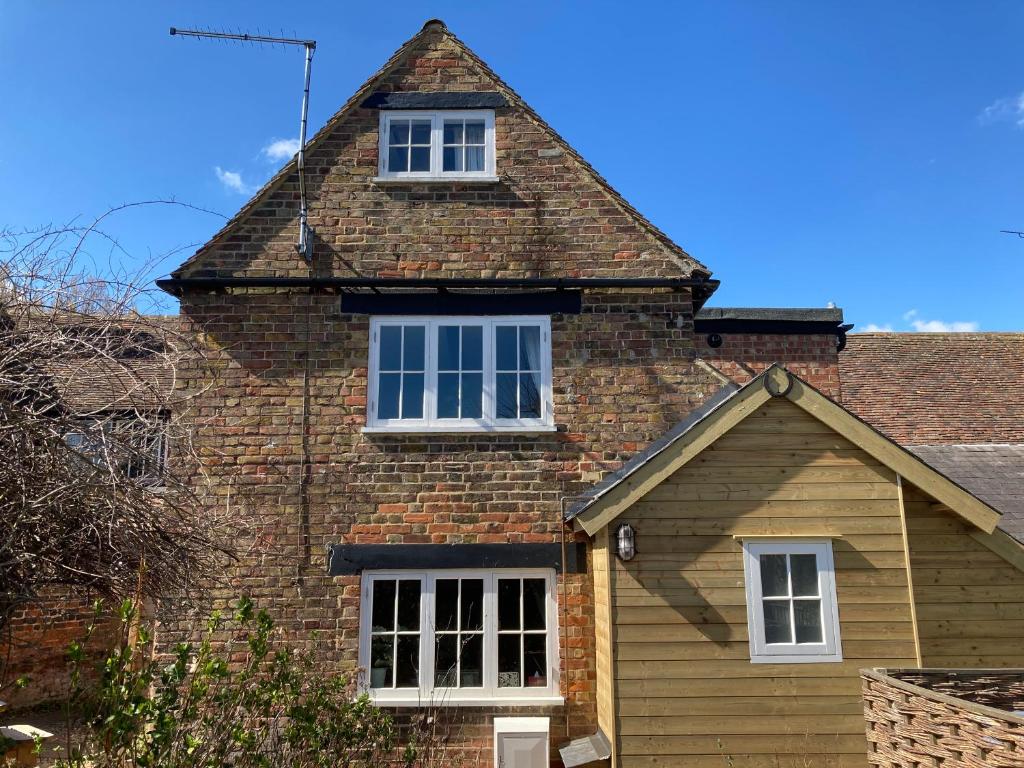 ein Backsteinhaus mit zwei Fenstern darüber in der Unterkunft Beautiful 500 year old listed Kentish cottage in Wingham