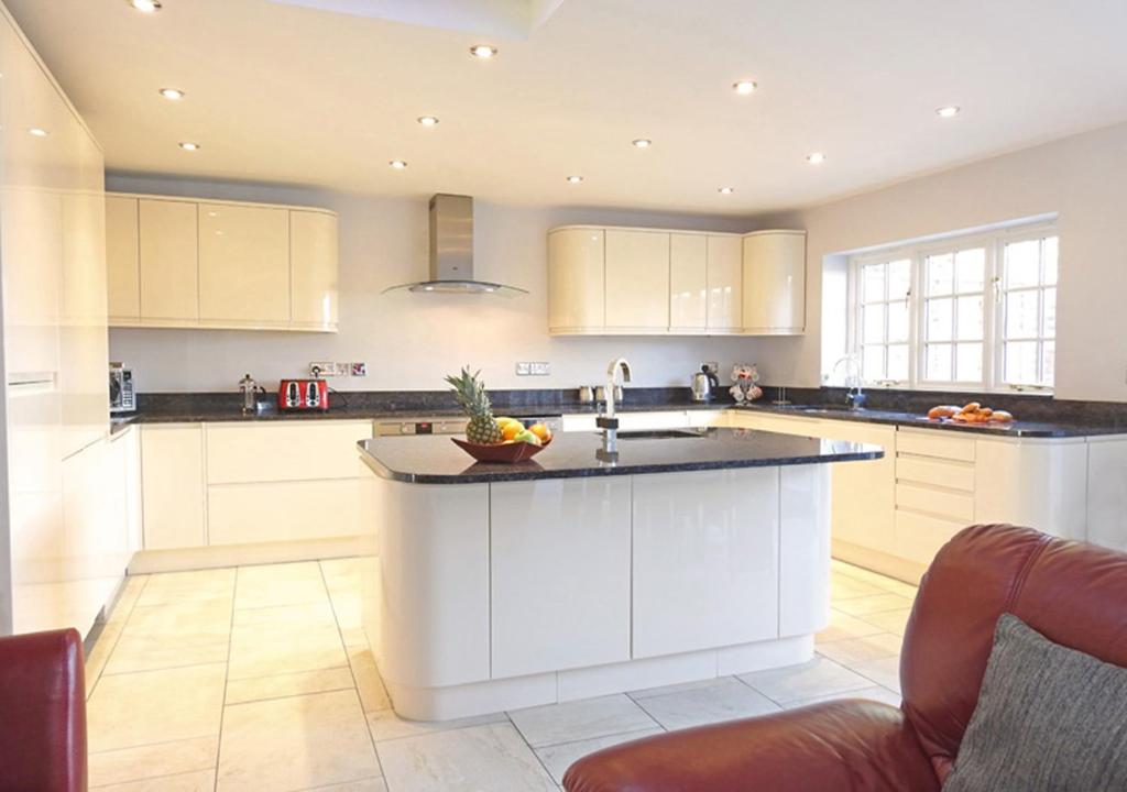 a kitchen with white cabinets and a large island at Coach House in Gosport
