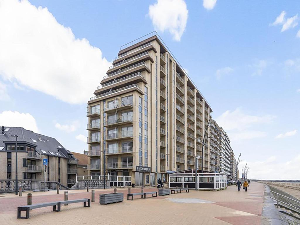 een hoog gebouw op het strand met banken ervoor bij Ocean Suites 815 - Appartment 2 bedrooms - floor 8 in Blankenberge