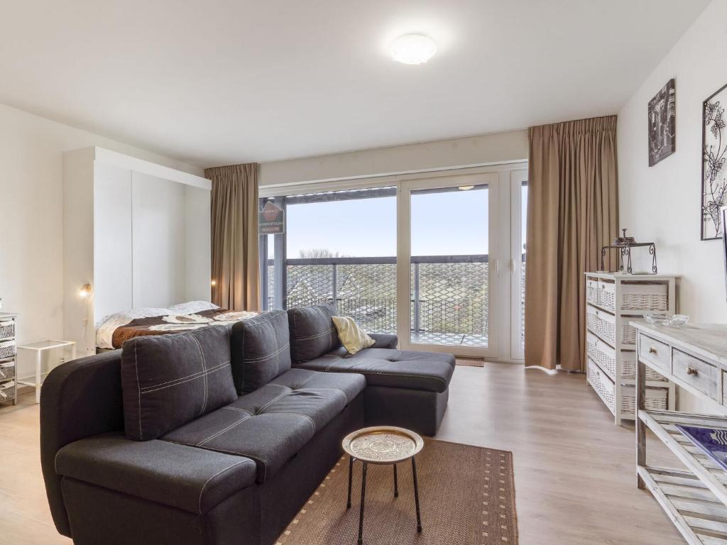 a living room with a couch and a bed at Spacious studio with storage room in Blankenberge