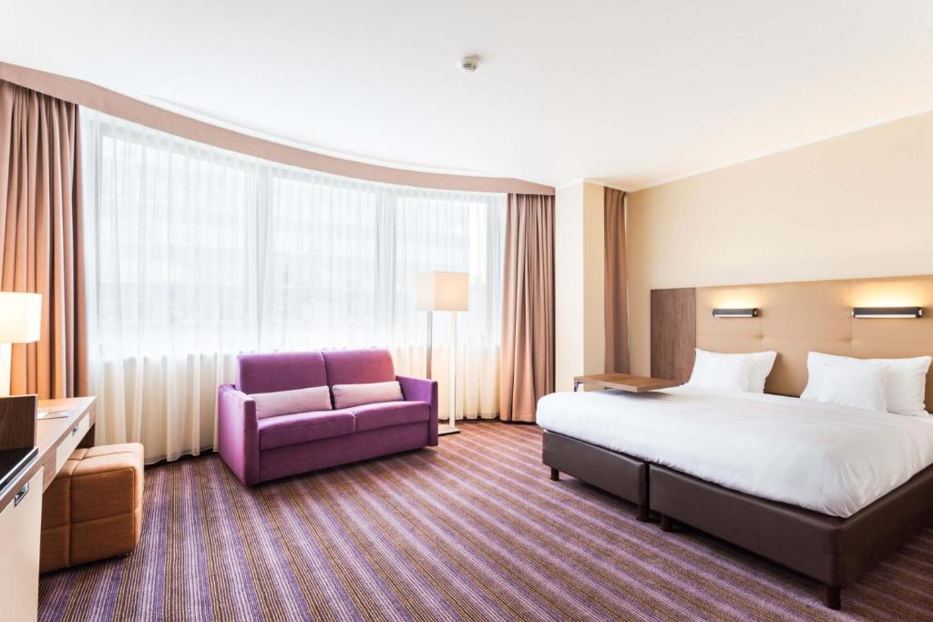 Hotel DeSilva Premium Poznań في بوزنان: غرفة في الفندق بسرير وكرسي ارجواني
