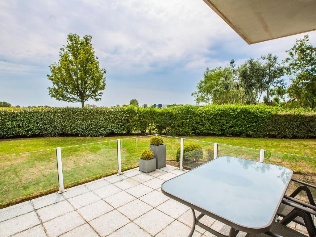 una mesa y sillas en un patio con vistas a un campo en Golf Azur Nice 0003 - Appartement 1 bedroom garage - floor 0, en Middelkerke