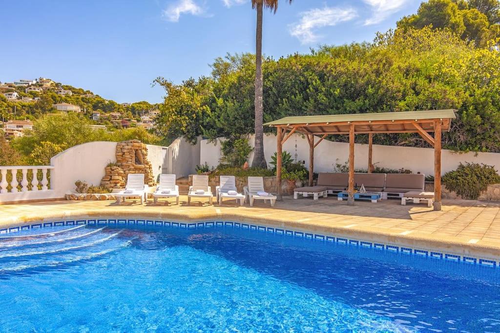 a swimming pool with chairs and a gazebo at Villas Guzman - Matisse in Moraira