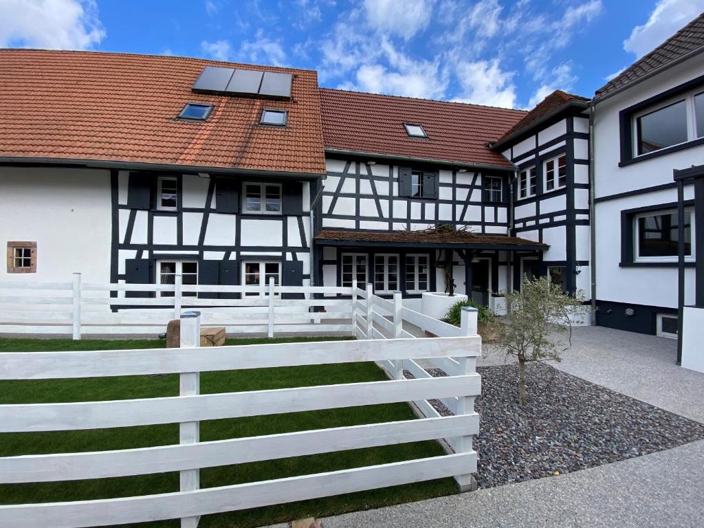 a white fence in front of a black and white house at A la ferme in Kurtzenhouse
