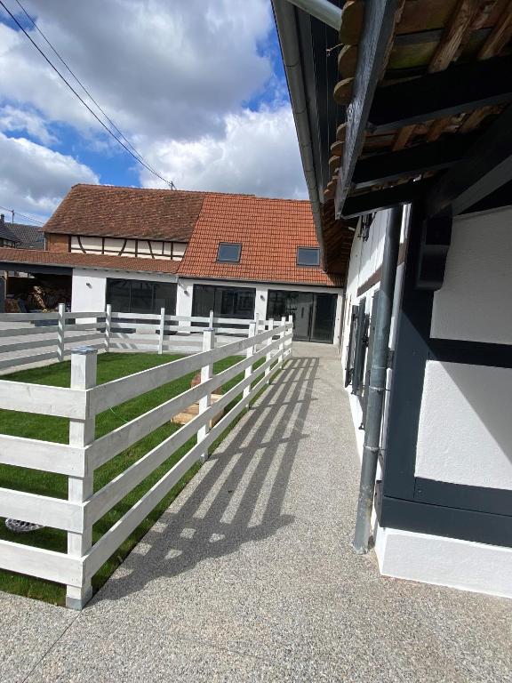 a white fence in front of a house at A la ferme in Kurtzenhouse