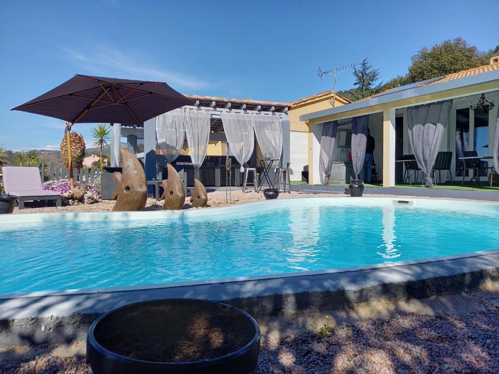 a swimming pool with an umbrella and chairs and a house at A Casa di Mariano in Alata