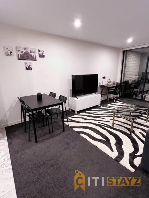 ein Wohnzimmer mit einem Tisch und einem TV in der Unterkunft Black & White Delight - 2bd 2bth Apt - Braddon in Canberra