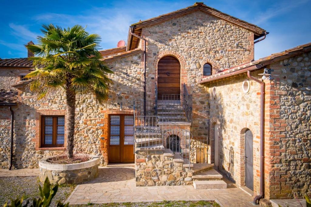 a stone house with a palm tree in front of it at Ulivo-Chianti Charming Flat with Private Parking! in Asciano