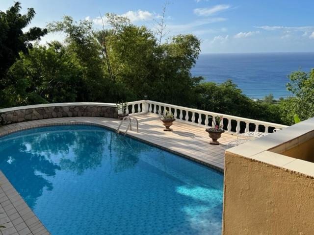 a swimming pool on a balcony with the ocean in the background at Famili Villa in Old Towne