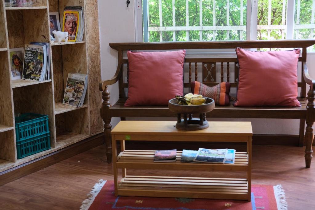 a room with a bench with pillows and a table at @Home Hostel Wua Lai in Chiang Mai