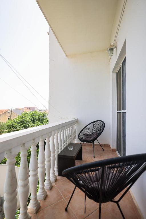 a balcony with two black chairs and a window at Apartments Marina in Petrcane