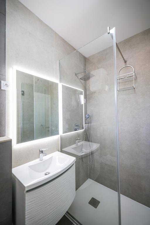 a white bathroom with a sink and a shower at Apartments Marina in Petrcane