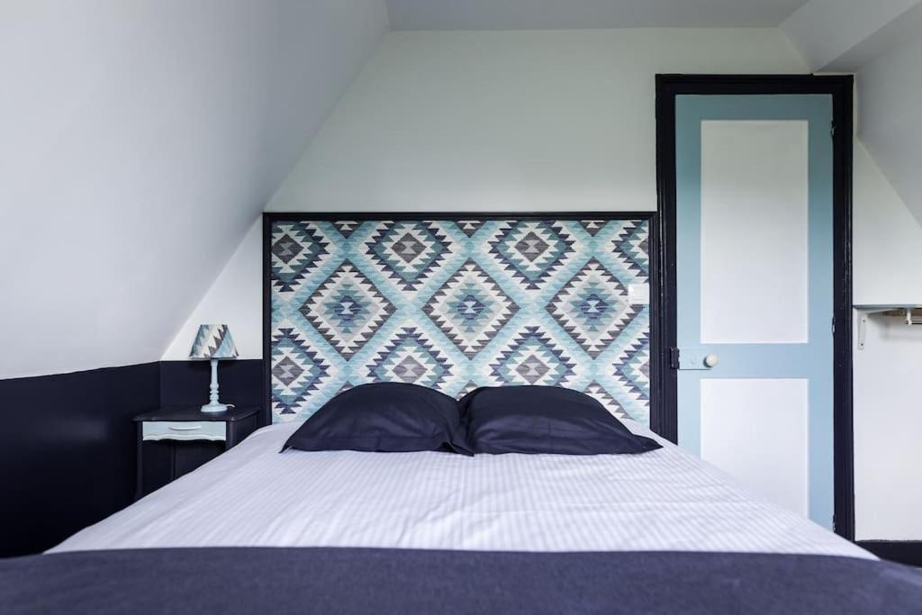 ein Schlafzimmer mit einem großen Bett mit einem großen Kopfteil in der Unterkunft La Villa de l'Etoile 10 personnes in Forges-les-Eaux