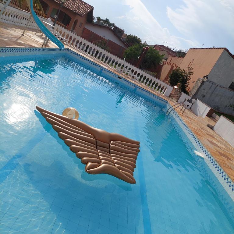 a large swimming pool with a brown plastic wing on it at Recanto Panapaná - suítes in Águas de São Pedro