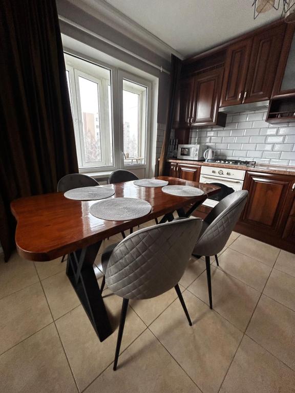 a kitchen with a wooden table and chairs in it at Апартаменти на виставці in Khmelnytskyi