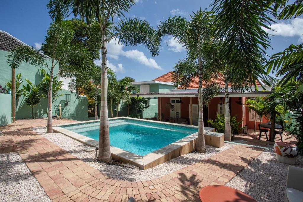 een zwembad voor een huis met palmbomen bij Historical city villa in Willemstad
