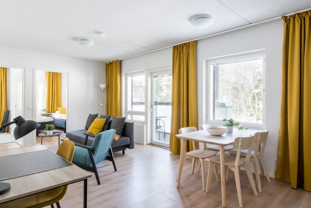 uma sala de estar com cortinas amarelas e uma mesa e cadeiras em Hiisi Homes Kirkkonummi Laajakallio em Kirkkonummi