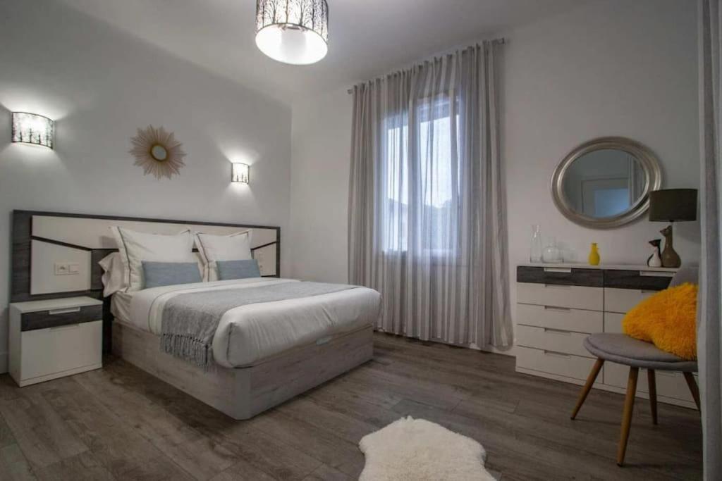 a white bedroom with a large bed and a mirror at Appartement T3 en villa in Hendaye