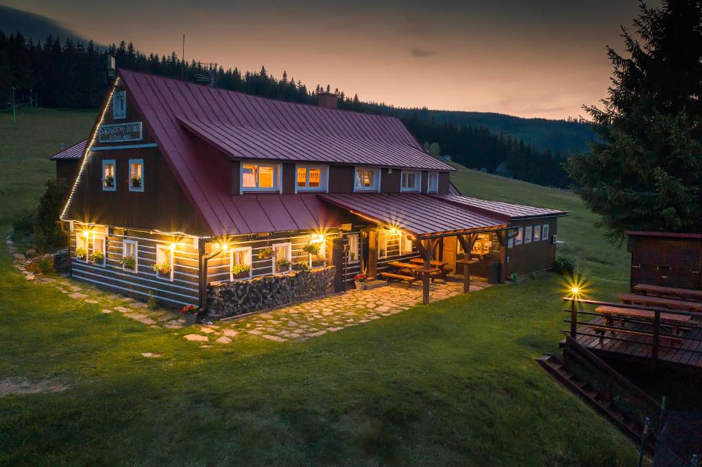 een groot houten huis met 's nachts verlichting bij Sagasserovy boudy U Dvou vleků in Pec pod Sněžkou