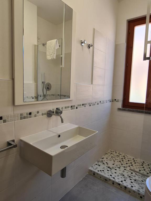 a white bathroom with a sink and a mirror at Villaggio Mietta in Castiglioncello