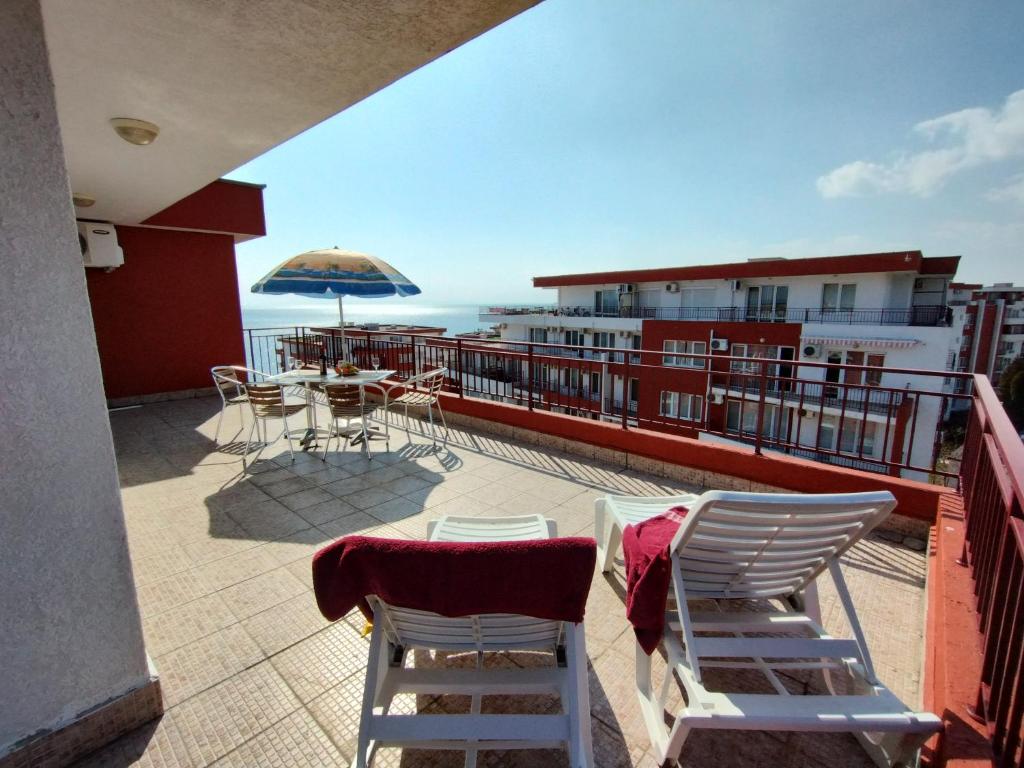a balcony with a table and chairs and an umbrella at Apartament Panorama - BastetBS in Sveti Vlas