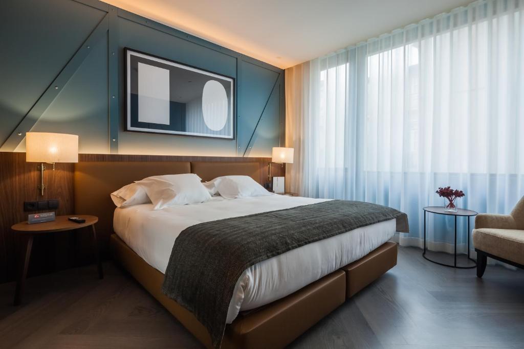 a hotel room with a large bed and a chair at Vincci Porto in Porto