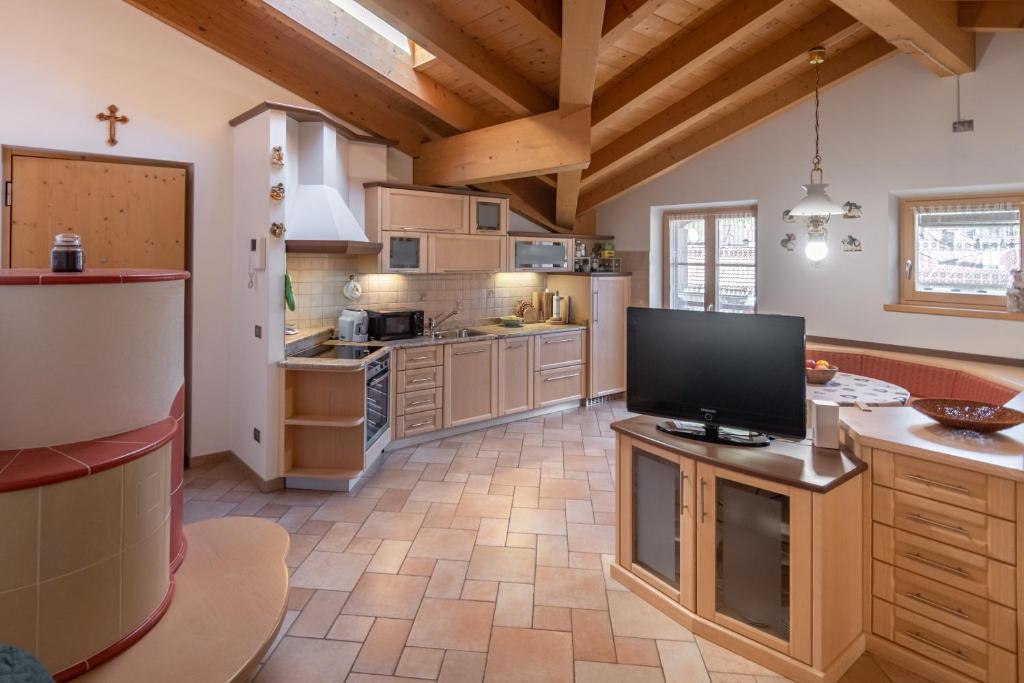 eine große Küche mit Holzschränken und einem Flachbild-TV in der Unterkunft DolomiApartments - Appartamento Coronelle in Predazzo