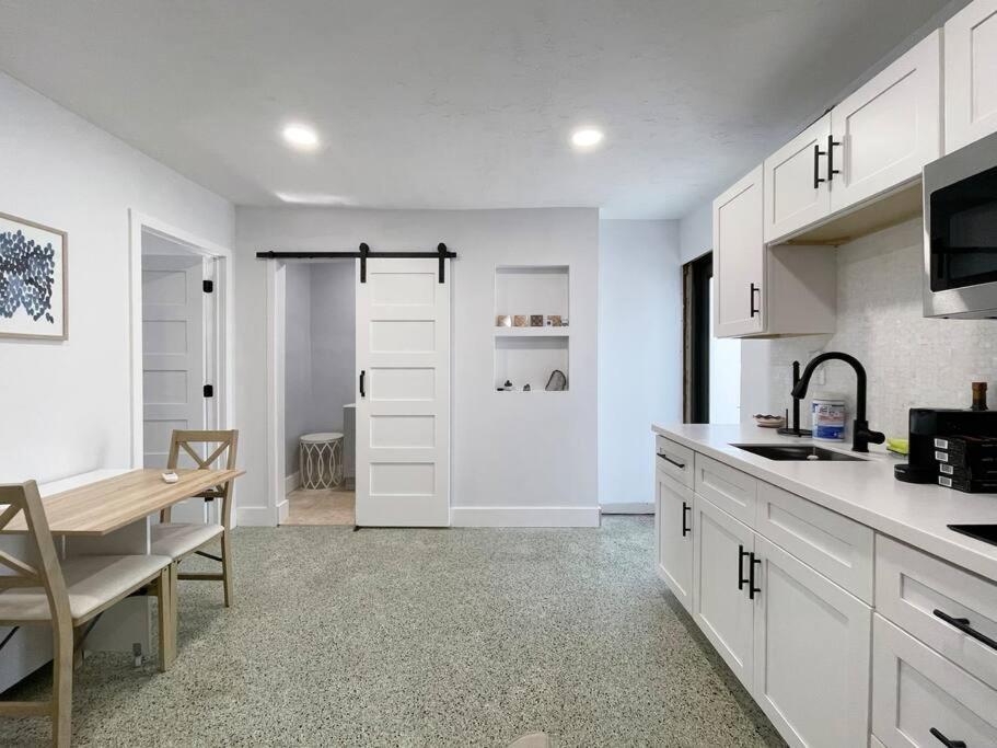 una cocina con armarios blancos, una mesa y una puerta en Private King Suite in Miami, en Miami
