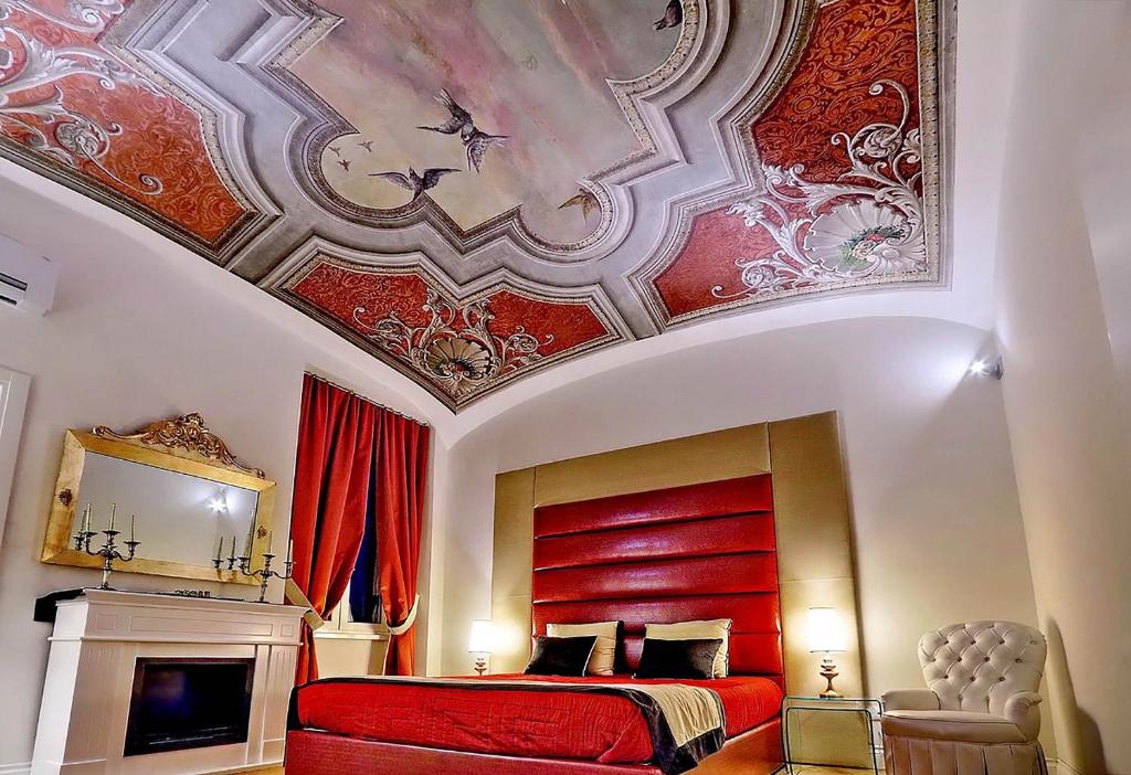 a bedroom with a red bed with a painting on the ceiling at AMM Luxury Rooms in Rome