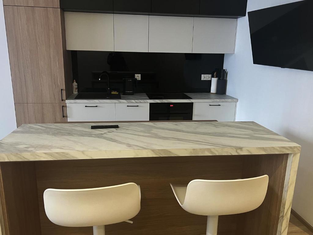 a kitchen with two white chairs at a counter at AMSTERDAM - nowy apartament w centrum z prywatnym zadaszonym parkingiem in Nowy Targ