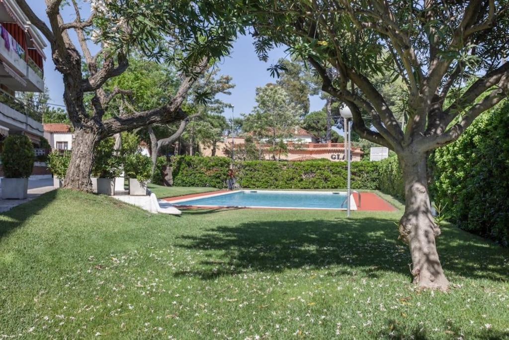 カステルデフェルスにあるHHBCN Beach Apartment Castelldefels #3の木々と芝生の庭のスイミングプール