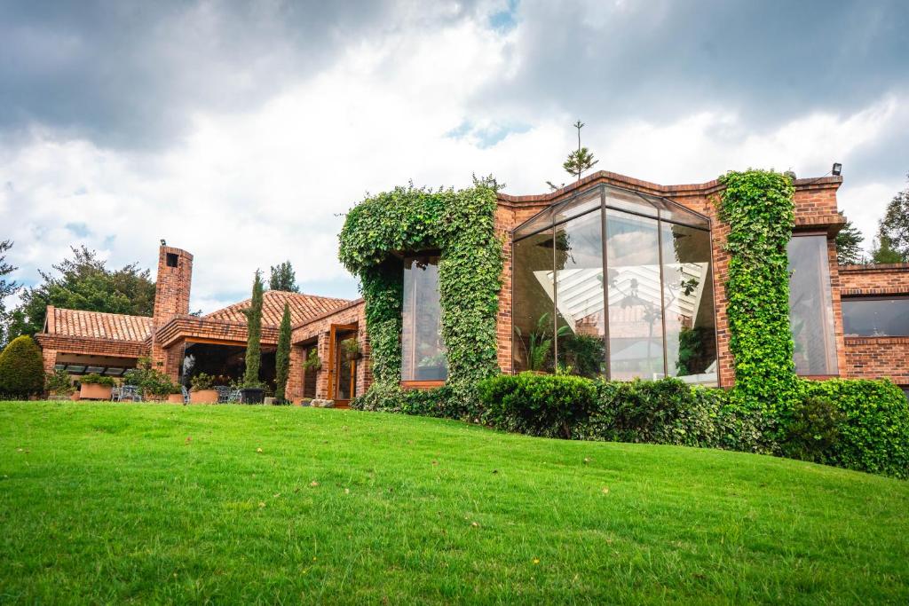 une maison en briques avec une cour verdoyante devant elle dans l'établissement Villa Los Lagos, à Bogotá