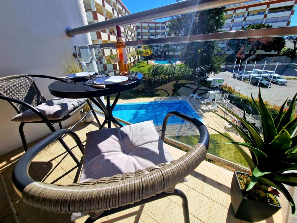 balkon ze stołem i krzesłami oraz basenem w obiekcie ZARCO - Apartment in Vilamoura with 2 Pools near the Beach & the Marina w mieście Quarteira