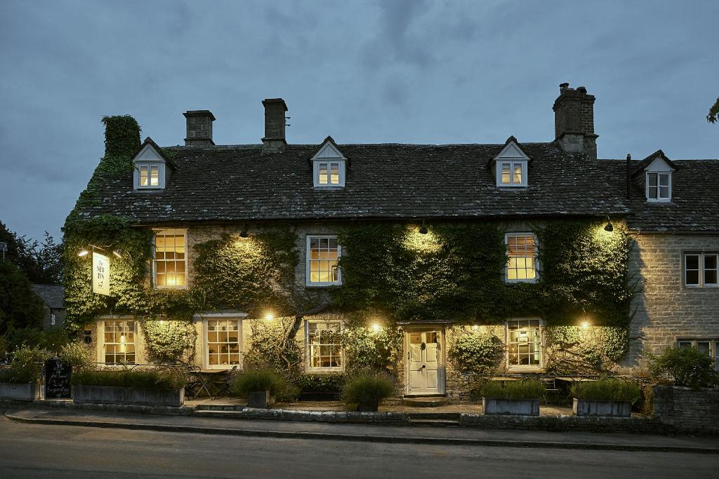 a large ivy covered building with lights on it at New Inn at Coln in Coln Saint Aldwyn